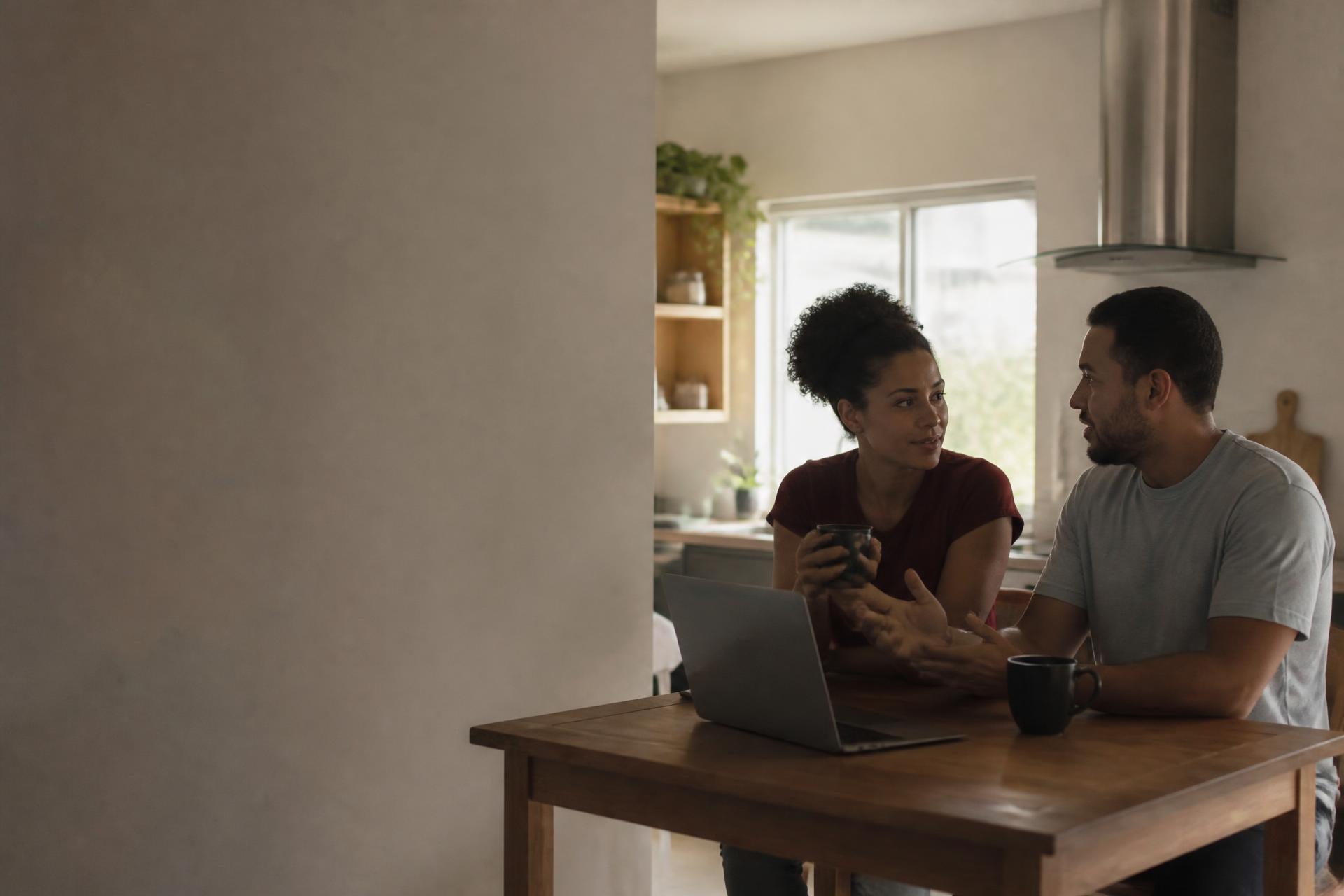Casal conversando sobre planos na mesa da cozinha, em uma manhã tranquila em casa